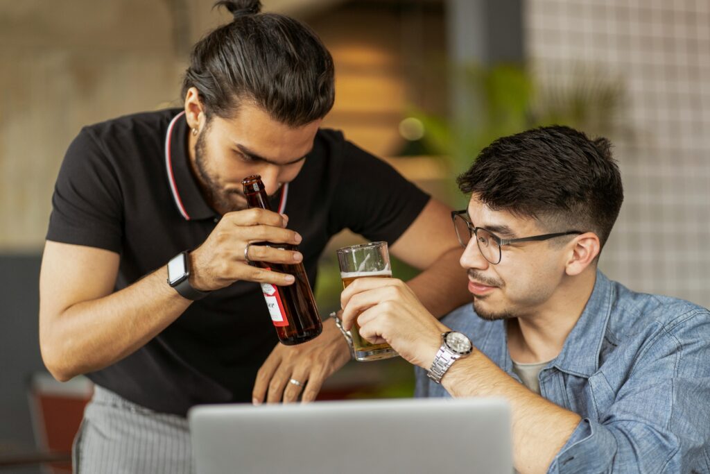 pexels-photo-5055743-5055743 Two men casually enjoying drinks while collaborating on a project in an indoor setting.